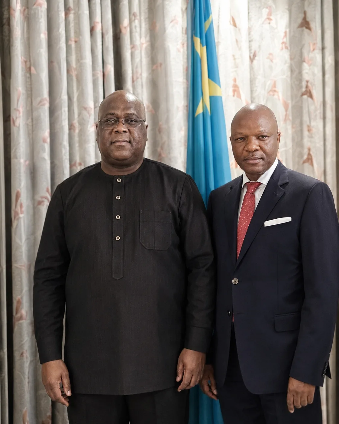 Monsieur Cibangu Civuadi debout aux côtés du Président Félix-Antoine Tshisekedi Tshilombo, devant le drapeau de la République Démocratique du Congo.